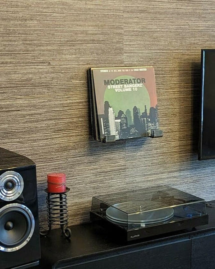 Modern entertainment center with black turntable, speaker, vinyl record, and wooden textured wall featuring The Jane J Sty...