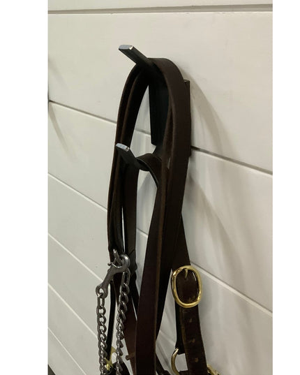 Black metal Elizabeth Wall Hook by Industrial Farm Co mounted on white shiplap wall holding dark leather horse bridle with...