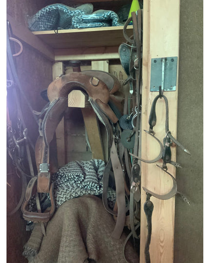 Marcellus Industrial Hook by Industrial Farm Co mounted on wooden tack room wall displaying horse saddles, bridles and equ...