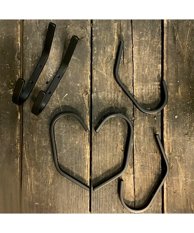 Black metal Stewart 1/2 inch wide double hooks by Industrial Farm Co displayed on weathered wooden planks, showing curved ...