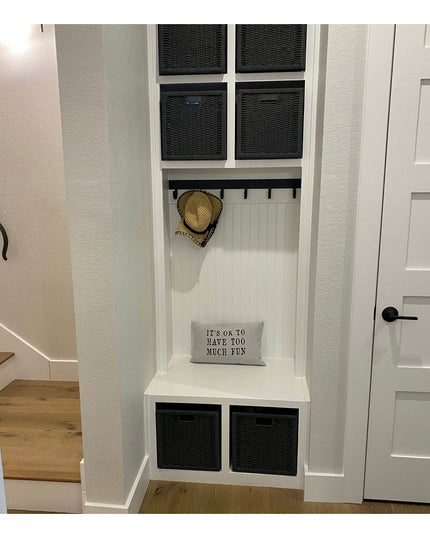 White built-in mudroom storage unit with black wicker baskets, bench seating, coat hooks, and beadboard backing from Indus...