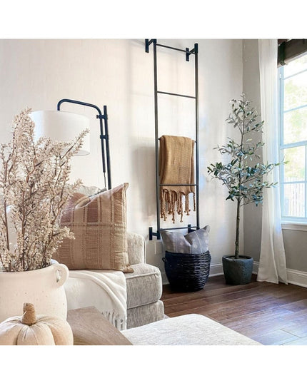 Black metal wall-mounted Ossit ladder from Industrial Farm Co displaying woven throw blanket in modern living room with ne...