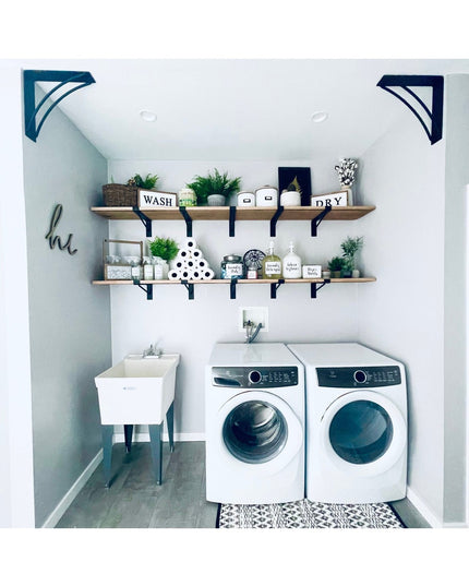 Black metal Nauseef shelf support brackets holding wooden shelves in modern white laundry room with washer and dryer