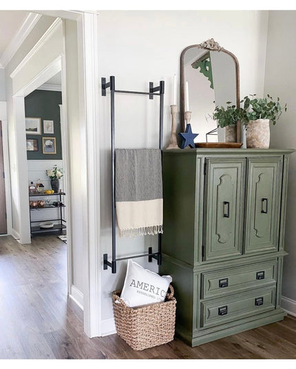 Black metal wall mounted Ossit ladder by Industrial Farm Co displaying gray and cream striped throw blanket in farmhouse s...