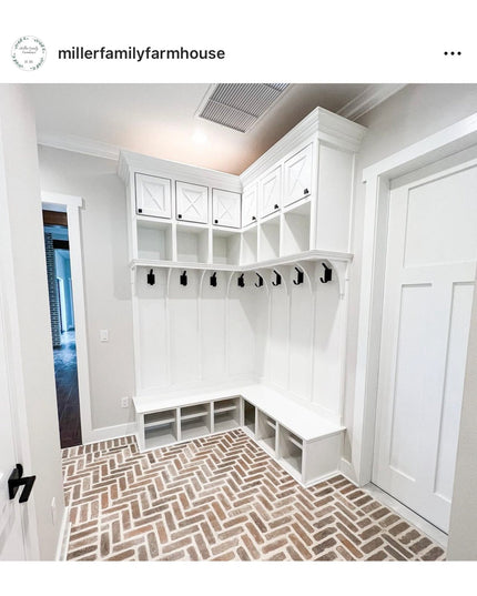 White farmhouse mudroom with built-in storage cubbies, bench seating, upper cabinets, and black wall hooks including The E...