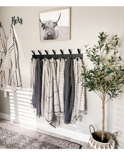 Black metal wall-mounted Fairmount Style Coat Rack by Industrial Farm Co with multiple hooks holding neutral striped towel...