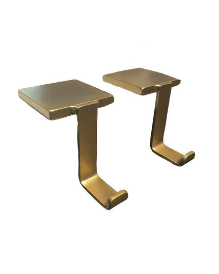 Pair of brass-finished Annie Stocking Holders by Industrial Farm Co, featuring curved C-shaped hooks with flat mounting pl...