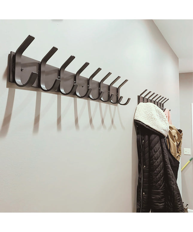 Black wall-mounted metal coat rack with multiple hooks displaying quilted jacket with sherpa collar, modern industrial des...