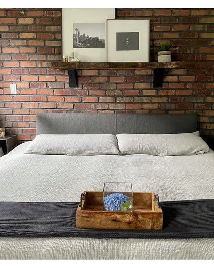 Heavy duty black steel Albany 4" industrial shelf brackets from Industrial Farm Co supporting floating shelf above bed wit...