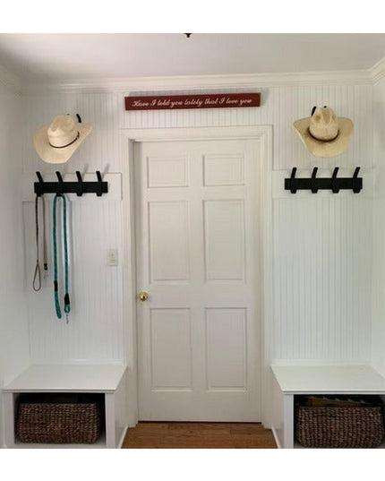 The Fairmount Style Coat Rack by Industrial Farm Co in black metal mounted on white mudroom wall with cowboy hats and leashes