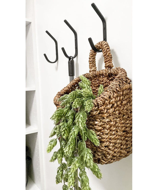 Black iron Stewart 1/2" Wide Double Hook mounted on white wall with woven basket and green fern, Industrial Farm Co wall hook
