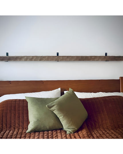 Heavy duty black steel L-shaped shelf brackets mounted under rustic wood beam shelf above bed with green pillows - Industr...