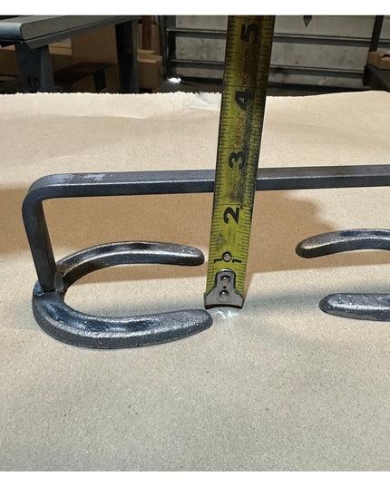Black wrought iron horseshoe door handle by Industrial Farm Co showing curved horseshoe design with measuring tape for sca...