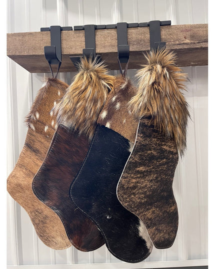 Industrial Farm Co Annie Stocking Holder displaying four fur Christmas stockings in brown and black cowhide with fur cuffs...