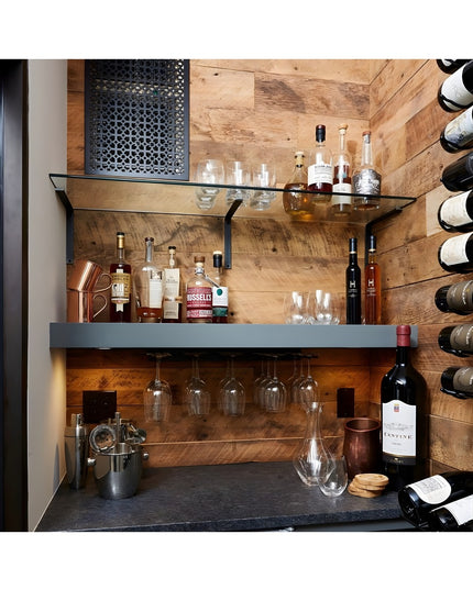 Modern home bar with black steel L-shaped shelf brackets supporting glass shelves, displaying liquor bottles and glassware...