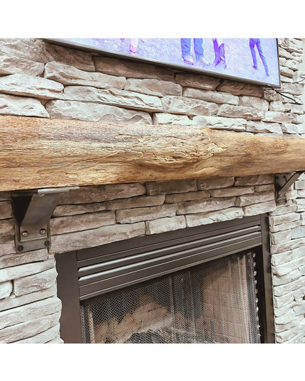 Rustic wood beam mantel with Ithaca bracket supports mounted on stone fireplace wall, showing natural wood grain and metal...
