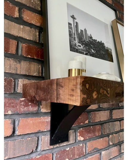 Black steel Albany 4-inch industrial shelf bracket with curved support bar mounted on brick wall supporting wooden shelf w...