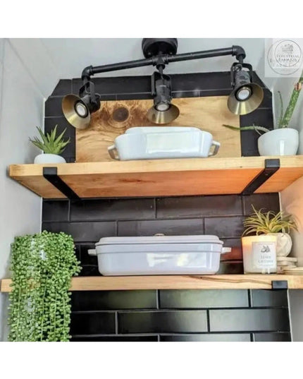 Industrial-style black metal Jane J shelf brackets supporting wood shelves with ceramic dishes, plants, and industrial pip...