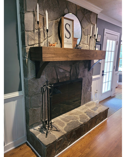Rustic stone fireplace featuring Eleanor Minimal Steel Brackets supporting wooden mantel, with candles and round mirror in...