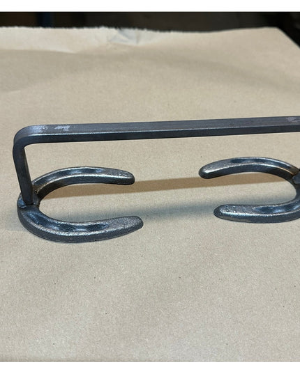 Black wrought iron Chincoteague Pony Shoe Door Handle by Industrial Farm Co, featuring horseshoe-shaped design on beige su...