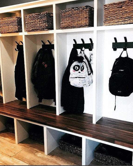 White built-in mudroom storage cubbies with dark wood bench seats, wicker baskets on top shelf, and black Fairmount Style ...