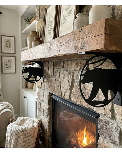 Black metal bear cutout L-bracket shelf supports holding rustic wood mantel on stone fireplace in cozy living room
