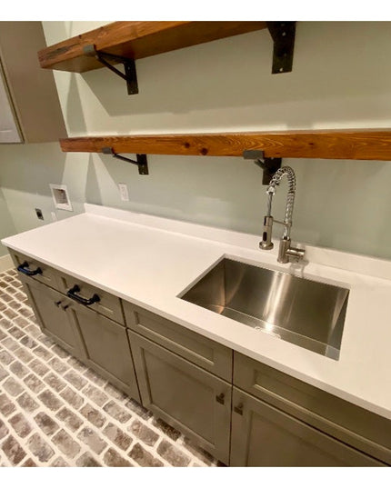 Black metal Nauseef shelf support brackets holding rustic wood shelves in modern kitchen with white countertops and brick ...