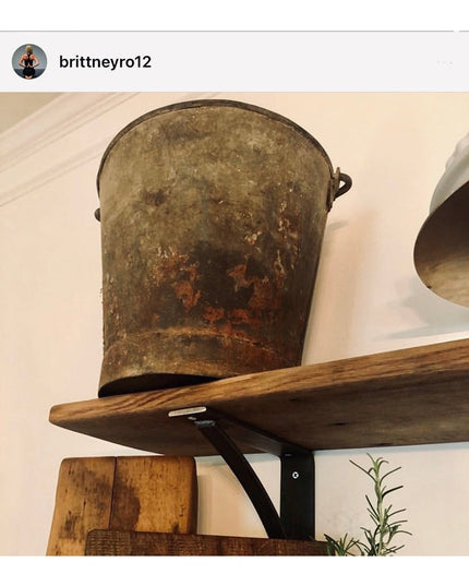 Rustic metal bucket displayed on wooden shelf supported by black curved steel industrial bracket from Industrial Farm Co