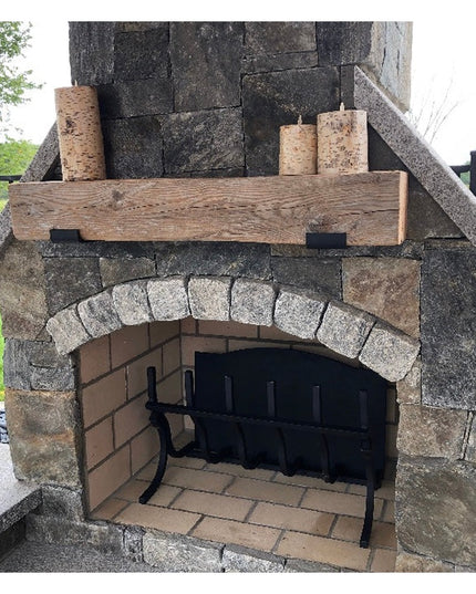 Rustic wood beam mantel with black metal brackets mounted on stone outdoor fireplace, showcasing Industrial Farm Co Glimme...