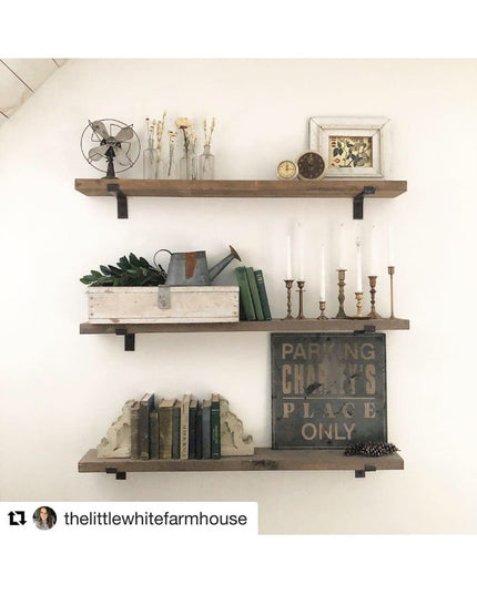 Rustic farmhouse floating shelves with black metal brackets displaying vintage decor including books, candlesticks, and pl...