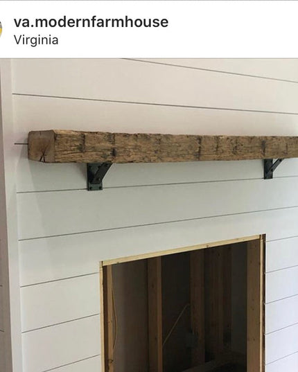 Rustic reclaimed wood mantel shelf with black metal Troy Shelf Support brackets mounted above white shiplap fireplace surr...
