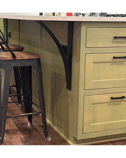 Black metal DeOrdio Modern Industrial Countertop Brackets supporting light wood kitchen island with drawers and bar stools