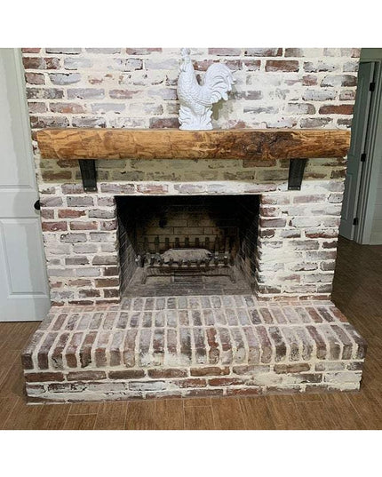 Rustic reclaimed wood mantel with black metal Jeffery Style Shelf Brackets mounted on whitewashed brick fireplace by Indus...
