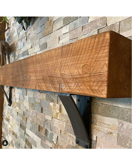 Industrial Farm Co Jeffery Style black metal shelf bracket supporting rustic wood beam mantel against stone brick wall