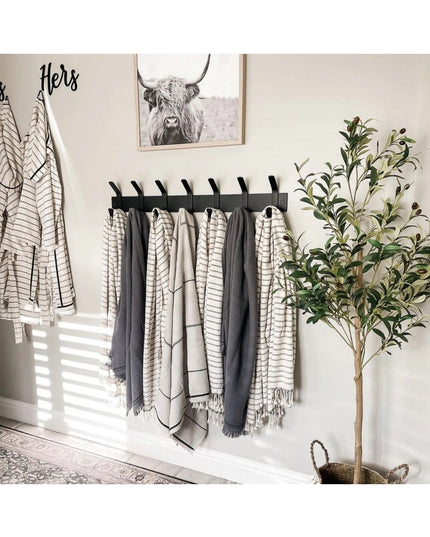 Black wall-mounted Fairmount Style Coat Rack by Industrial Farm Co with 8 hooks holding neutral striped towels and blanket...