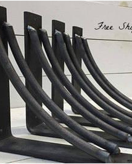 Set of four black metal curved shelf brackets called The Niagara Bracket Support by Industrial Farm Co against white shipl...