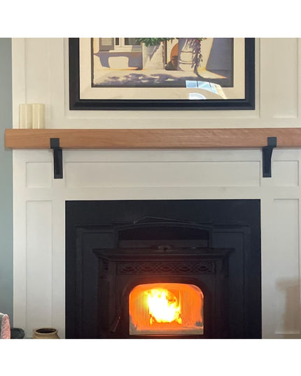 Black metal Saratoga Shelf Support Brackets by Industrial Farm Co supporting natural wood mantel above white fireplace