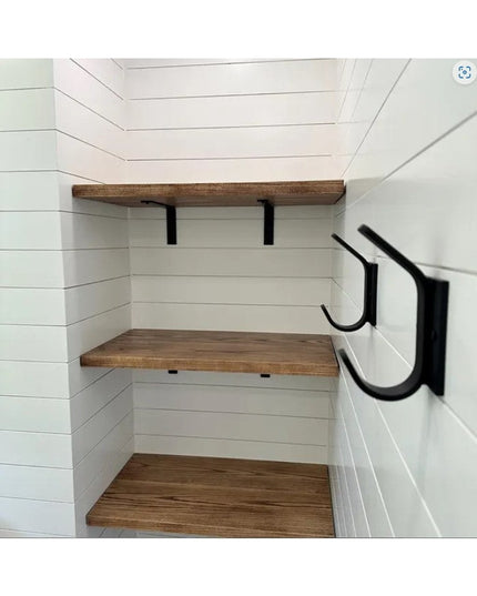 Black metal Elizabeth Wall Hooks by Industrial Farm Co mounted on white shiplap walls in mudroom with wooden shelves and b...
