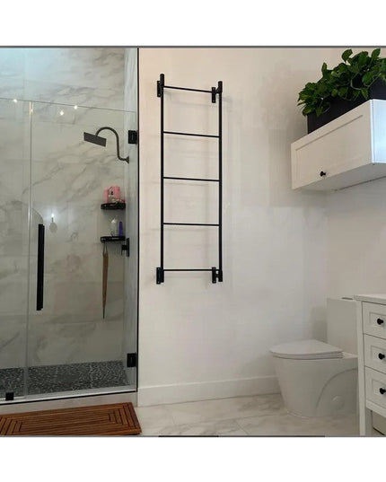 Black metal Wall Mounted Ossit Ladder by Industrial Farm Co installed in modern white bathroom next to glass shower and va...