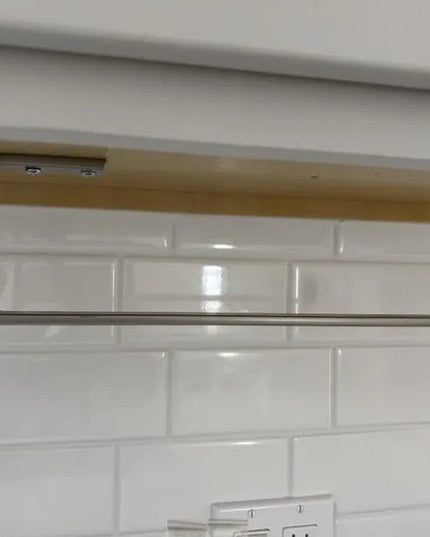 Industrial Farm Co Jordan Paper Towel Holder in brushed steel finish mounted under kitchen cabinet above white subway tile...