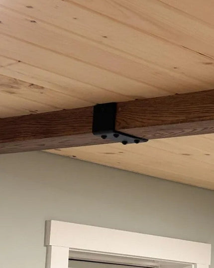 Black metal Billings Wooden Beam Strap from Industrial Farm Co wrapping around natural wood ceiling beam in rustic interior