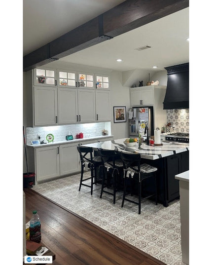 Dark wood beam straps wrapping exposed ceiling beams in modern farmhouse kitchen with white cabinets and black island - In...