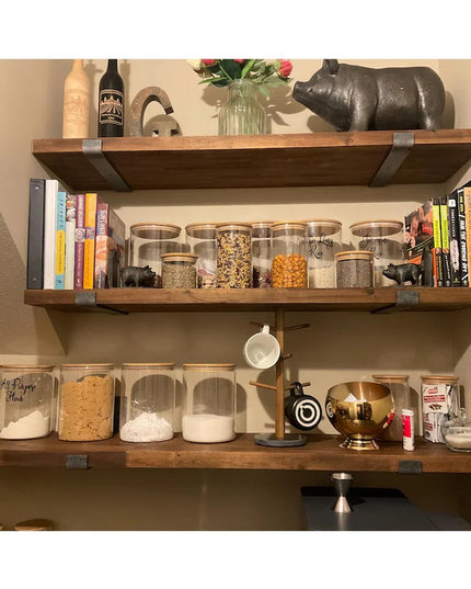 Industrial Farm Co Jane J Style black metal shelf brackets supporting rustic wood shelves with glass storage jars and kitc...