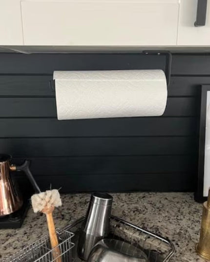 Black slatwall-mounted Jordan Paper Towel Holder by Industrial Farm Co displayed in modern kitchen with granite countertop...