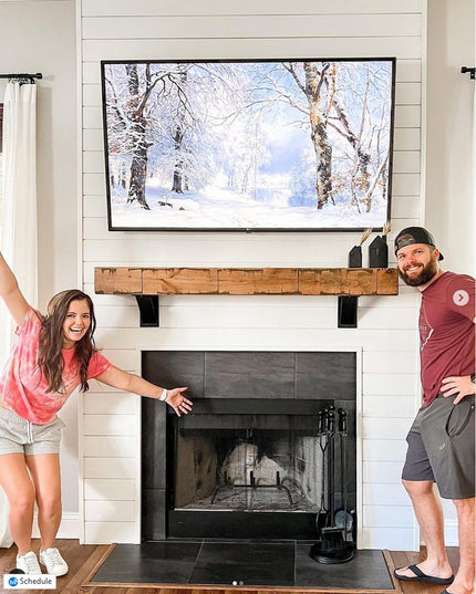 Industrial Farm Co Albany black steel shelf brackets supporting rustic wood mantel beneath mounted TV over modern fireplace