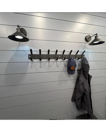 Black metal Fairmount Style Coat Rack with 8 hooks mounted on white shiplap wall, displaying gray jacket and navy cap with...