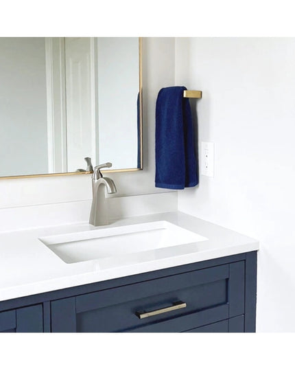 Modern bathroom vanity featuring navy blue cabinets with brass Emma Towel Holder by Industrial Farm Co, white countertop a...