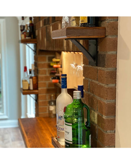 Heavy duty steel Albany 4" industrial shelf bracket in black with curved support bar mounted on brick wall supporting wood...