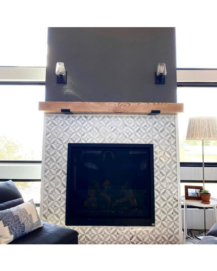Black metal Glimmerglass J Shelf brackets supporting wood mantel above white geometric tile fireplace surround