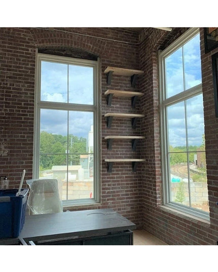 Industrial Farm Co Albany black steel shelf brackets with curved support bars mounted on exposed brick wall holding wooden...